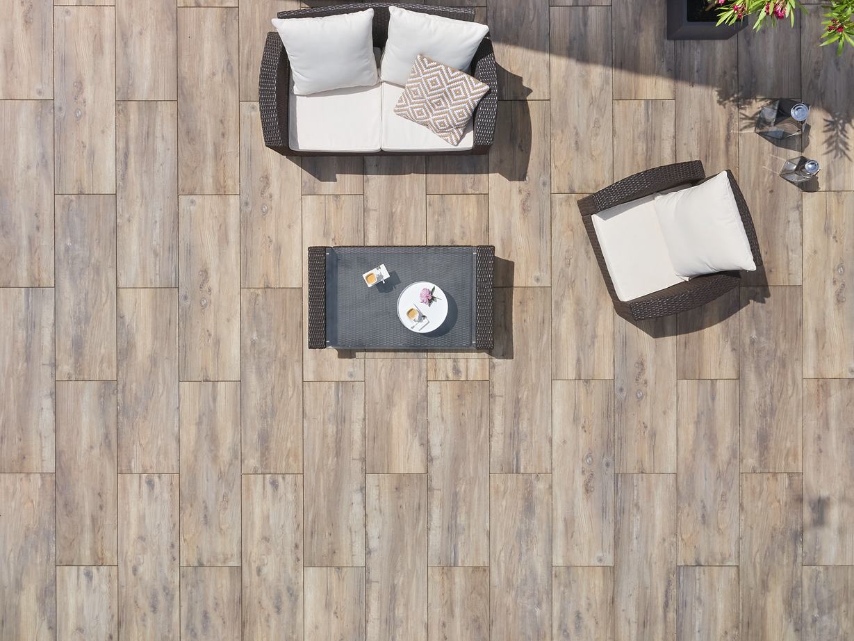 Vogelvlucht van een terras met houtlook platen en modern meubilair