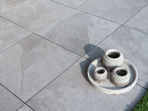 Lichtgrijze keramische terrastegels Alpine Grey met decoratie