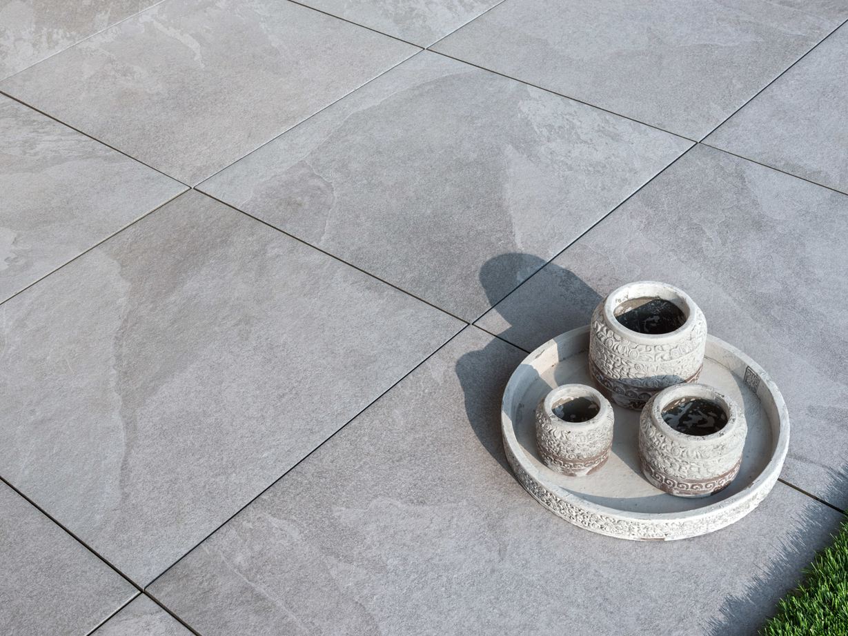 Lichtgrijze keramische terrastegels Alpine Grey met decoratie