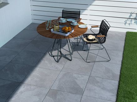 Terras met tuinmeubilair en lichtgekleurde platen in gedeeltelijke schaduw