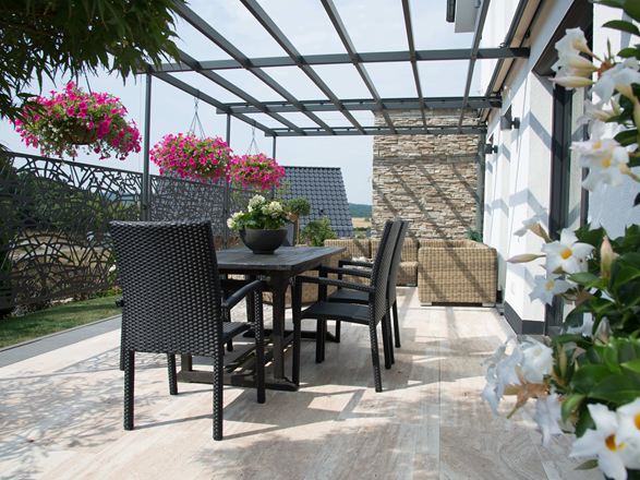 Terras met donker tuinmeubilair en houtachtige Natura travertin vloeren
