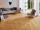Grijze moderne bank met fauteuil op Urban Honey houtlook porcellanato tegels in een lichte woonkamer