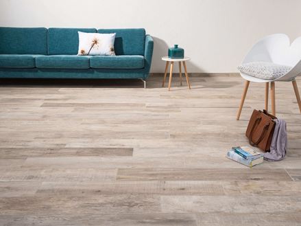 Woonkamer met Indie Sky houtlook tegels, witte stoel en donkergroene bank