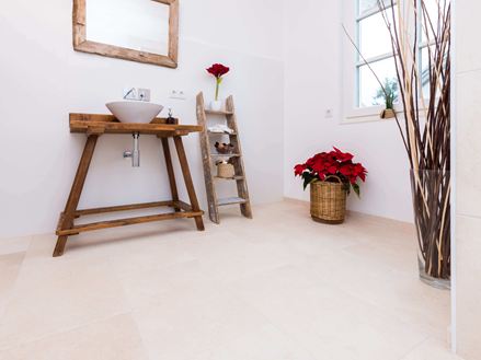Badkamer met houten meubilair en lichtgekleurde tegels van natuurlijk kalksteen als vloerbedekking