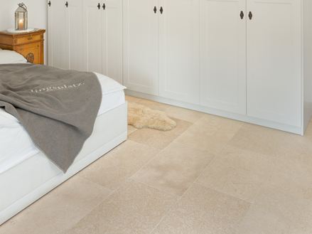 Slaapkamer met witte kledingkast en wit bed, beige kalkstenen tegels op de vloer