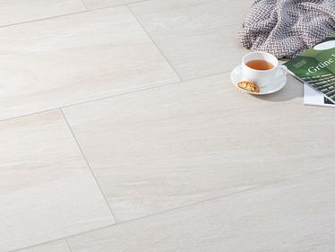 Lichtbeige steenlook tegels met een koffiekopje en een deken erop