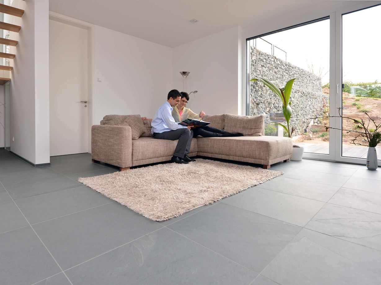 Groot formaat Grey Slate leisteen tegel in de woonkamer met lichtgekleurde bank en witte muren. Een stel zit op de bank