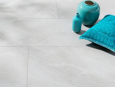 Keramische tegels in lichtgrijze leisteenlook met turquoise vaas en turquoise kussen