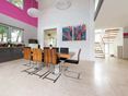 Heldere kleuren: uitstekende combinatie Open eethoek met moderne houten stoelen en kleurrijk schilderij aan de muur, vloer van lichte travertin tegels met geschuurd oppervlak