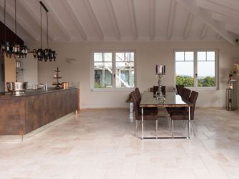 Lichte travertin tegels in een gemengd patroon in een moderne keuken met eettafel en kookeiland