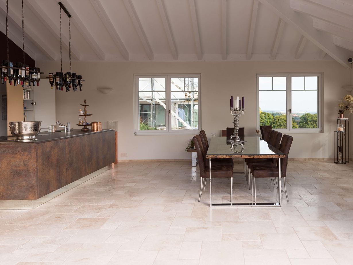 Lichte travertin tegels in een gemengd patroon in een moderne keuken met eettafel en kookeiland