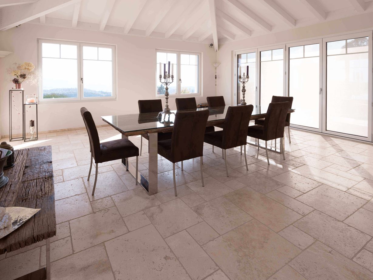 Eetkamer met hoog plafond, tafel en stoelen op Travertin Licht in Romeins verband