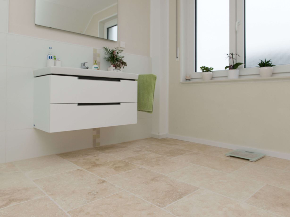 Lichte travertin tegel in moderne badkamer met wit meubilair
