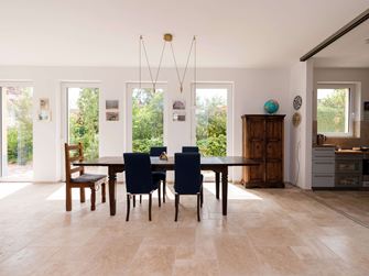 Lichte eethoek met houten meubels en beige travertin tegels als vloerbedekking