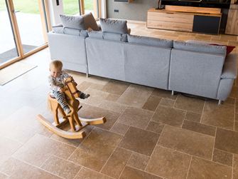 Kind zit op een hobbelpaard en speelt in de woonkamer met Noce SELECT travertinvloer
