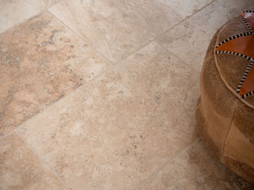 Rustieke travertin tegel gelegd in bruin en beige met decoratieve kussens