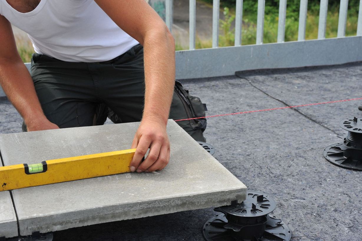 Platen worden op sokkels gelegd, de installateur gebruikt een waterpas